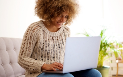 a young woman smiling and typing on her laptop